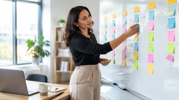 Responsable formation organisant des post-it sur un tableau blanc pour structurer un programme de formation