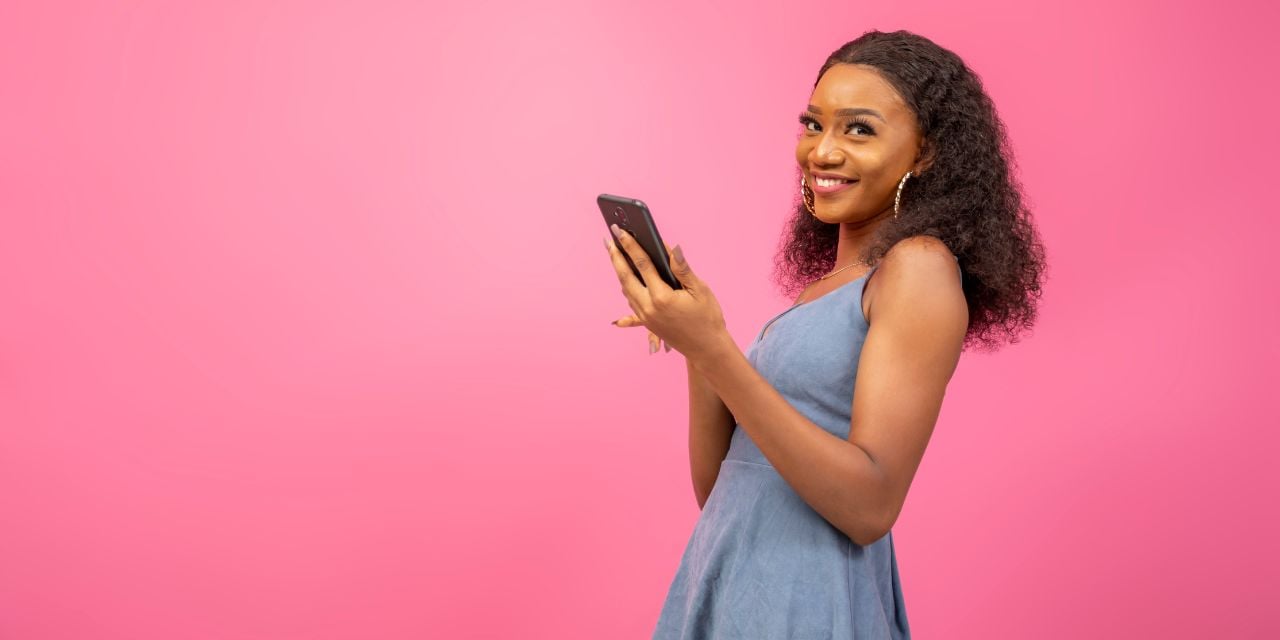 Une femme utilise sous smartphone avec un fond rose