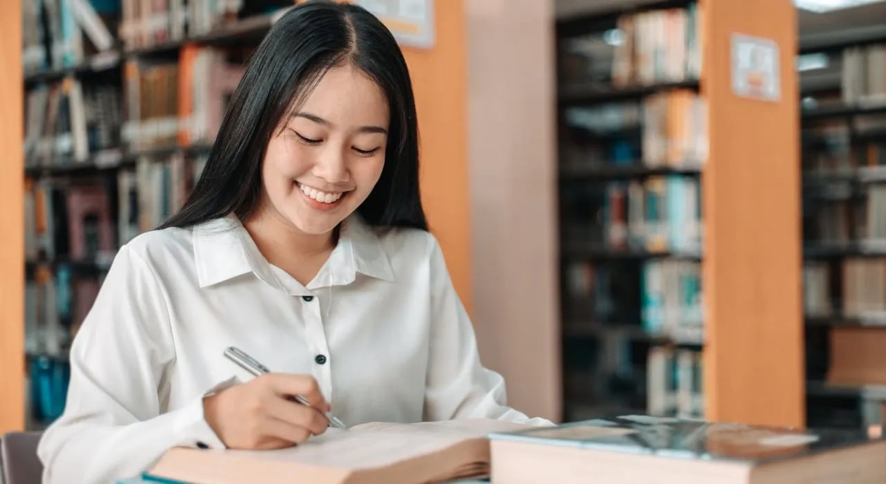 vrouw met boek glimlachend in bibliotheek